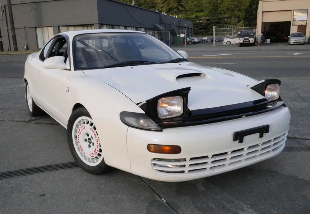 Toyota Celica con sus característicos faros escamoteables desplegados en una carretera.