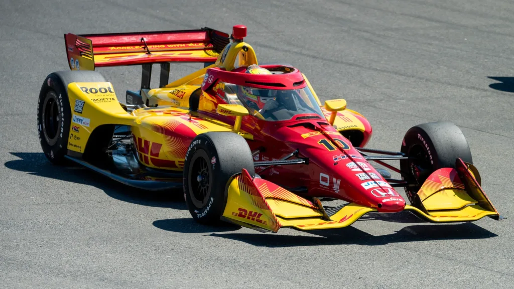 Alex Palou y Will Power en el podio del GP de Arlington 2026, con Kyle Kirkwood celebrando la victoria de Andretti