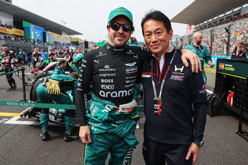 Fernando Alonso y Koji Watanabe conversando en el box de Aston Martin tras el GP de Japón, analizando la brecha de tres segundos.