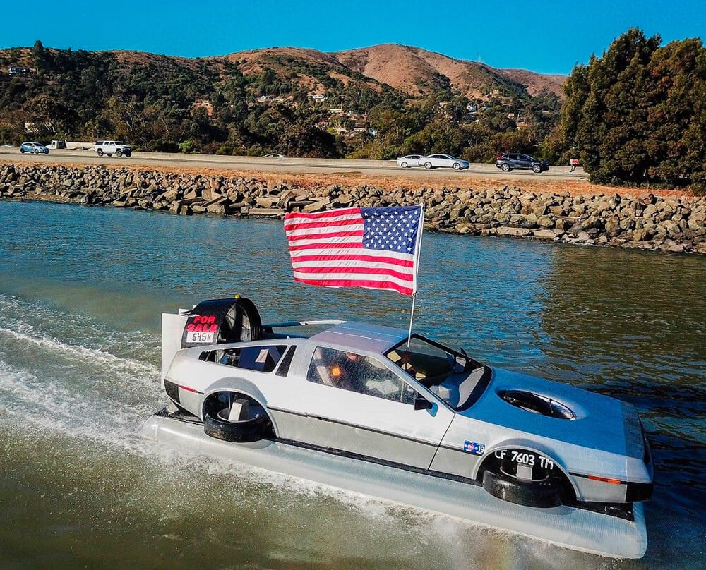 Matt Riese montado en el DeLorean Hovercraft luciendo una bandera americana